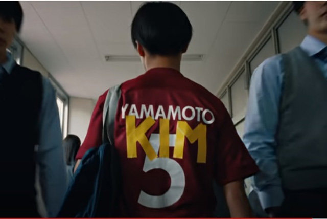 나이키의 새 광고에서 재일조선인 축구 선수(가운데)가 일본식 이름 ‘야마모토(YAMAMOTO)’ 위에 ‘김(KIM)’을 덧댄 유니폼을 입고 걸어가고 있다. 유튜브 화면 캡처