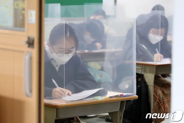 칸막이가 설치된 책상에서 마스크를 쓰고 대학수학능력시험 모의평가를 치르는 고3 학생들. © News1