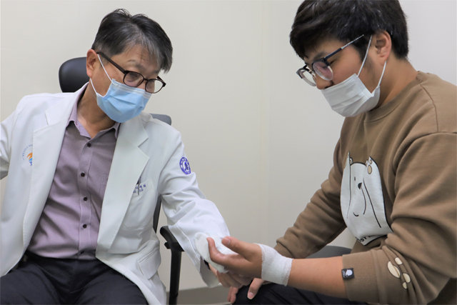 인하대병원 기세휘 교수(왼쪽)가 공장에서 작업 도중 왼손을 심하게 다쳐 3차례 재건술을 받은 김태경 씨의 손 상태를 살펴보고 있다. 인하대병원 제공