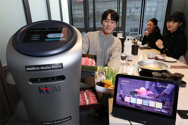 서빙로봇 고객이 ‘모던 샤브 하우스 광화문D타워점’에서 KT의 외식업계 디지털 혁신(DX) 시범 서비스를 체험하고 있다. 2세대 서빙로봇이 고객에게 서빙하고 있다.
