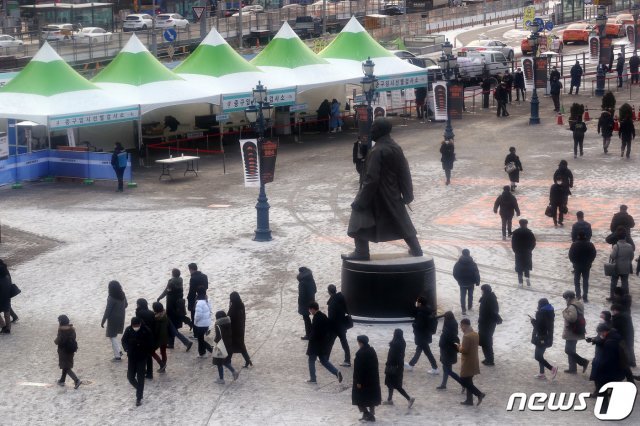 전날부터 내린 눈으로 도심 곳곳에 빙판길이 생긴 18일 오전 서울 중구 서울역광장에 마련된 코로나19 임시 선별진료소에서 검사를 받기 위해 줄 선 인파와 출근하는 시민들로 북적이고 있다. 2020.12.18/뉴스1 © News1