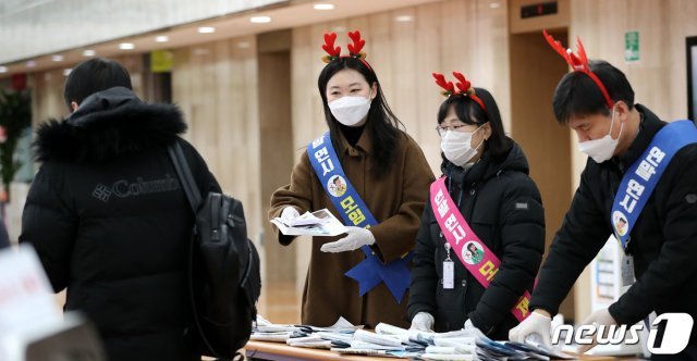 서울청사관리소 관리과 직원들이 21일 오전 서울 종로구 정부서울청사 입구에서 연말연시 신종 코로나 바이러스 감염즘(코로나19) 대응 방역수칙 준수 캠페인을 전개하고 있다. 이들은 코로나19 감염병 캠페인을 통해 연말연시 각종 모임 및 행사 자제를 당부했다. 2020.12.21 © News1