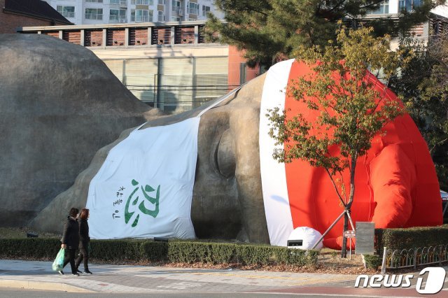 지난 6일 오후 대구 달서구 선사유적공원 진입로에 설치된 초대형 원시인 조형물에 산타 모자와 ‘참을 인(忍)’ 문구가 적힌 마스크가 씌워 있다.  2020.12.6 © News1