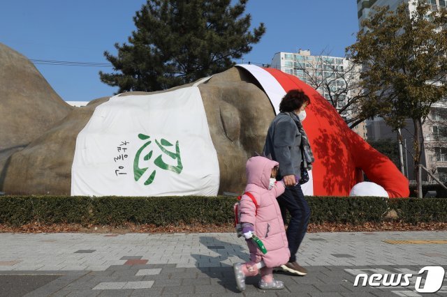 크리스마스를 하루 앞둔 24일 대구 달서구 선사유적공원 진입로에 산타 모자와 ‘참을 인(忍)’ 마스크가 씌워진 초대형 원시인 조형물이 잠들어 있다. 2020.12.24/뉴스1 © News1 공정식 기자