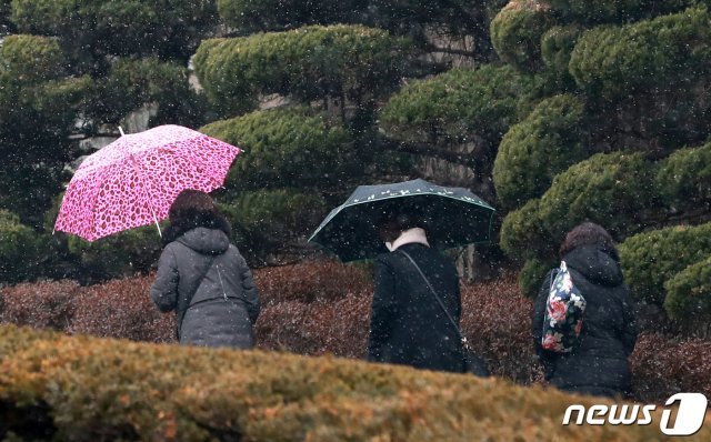 29일 오후 서울 종로구 신문로 일대에서 우산을 쓴 시민들이 내리는 눈을 맞으며 걷고 있다. 2020.12.29 © News1