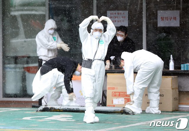 29일 오후 서울 구로구 미소들요양병원에서 의료진이 방호복을 갈아입으며 취재진에게 손하트로 인사하고 있다./뉴스1 © News1