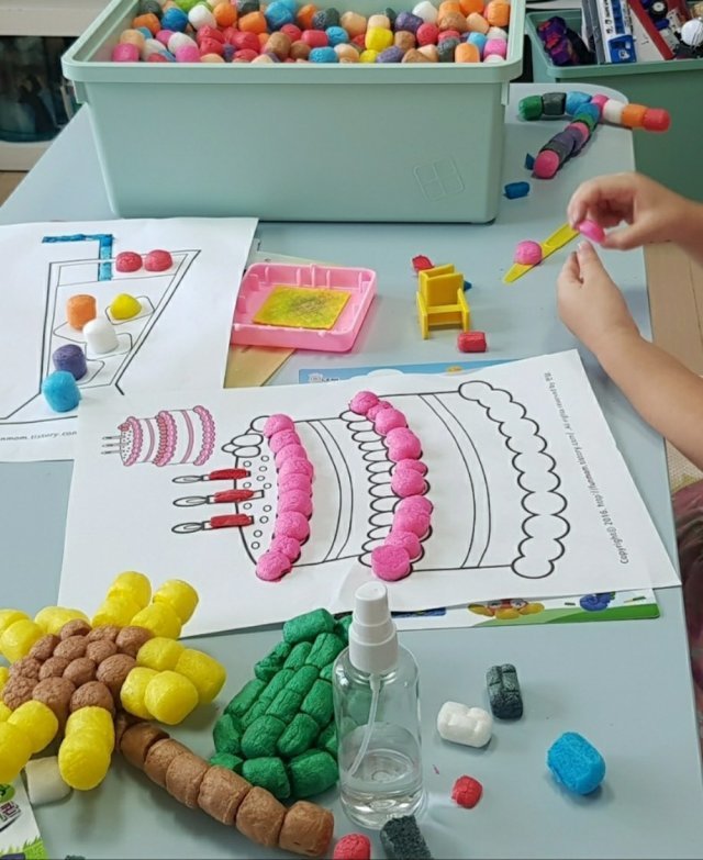 한 어린이가 케이크 모양이 인쇄된 종이
위에 형형색색의 스티로폼 조각을 붙이는
놀이를 하고 있다. 독자 제공