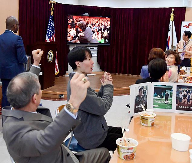 사진=해리 해리스 주한 미국대사(왼쪽)가 서울 종로구 주한 미국대사관에서 직원들과 ‘짜파구리’를 먹으며 아카데미 시상식을 시청하던 중 ‘기생충’ 작품상 수상 소식에 두 팔을 들며 환호하고 있다. 주한미국대사관 제공