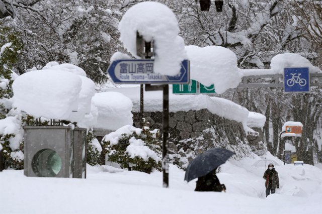 동해와 가까운 일본 호쿠리쿠 지방 도야마에서 시민들이 11일 가슴 높이까지 쌓인 눈 속에서 우산을 쓰고 걷고 있다. 도야마=AP 뉴시스