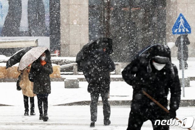 서울 전역에 대설주의보가 발령된 28일 서울 영등포구 여의도 일대에서 우산을 쓴 시민이 함박눈을 속을 걷고 있다. 2021.1.28 © News1