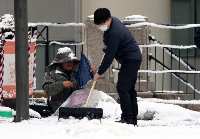 노숙인은 눈을 피하기 위해 선물 받은 우산을 폈다