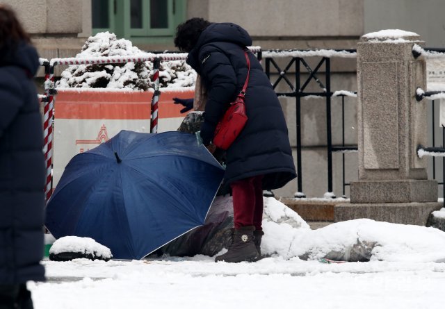 몇 걸음을 가던 시민이 다시 돌아와 머리의 눈을 털어주고 있다