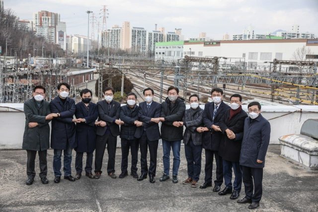 더불어민주당 우상호 의원(왼쪽에서 여섯 번째)이 지난달 31일 서울 광운대역에서 현장발표회를 열고 민주당 소속 의원들과 ‘X자 악수’를 하고 있다. 우상호 의원 페이스북