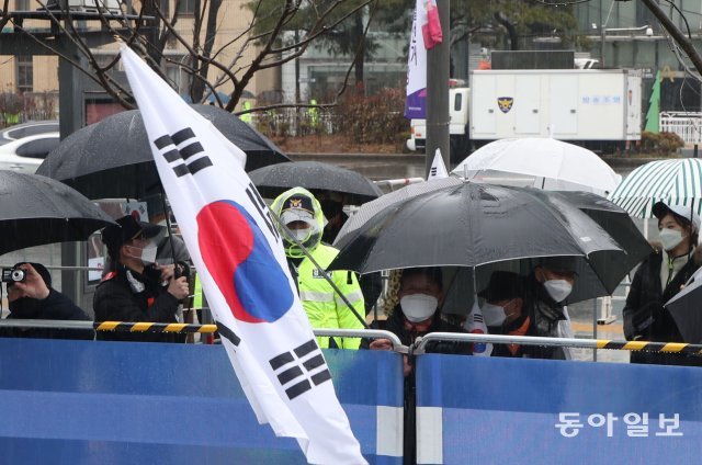 1일 서울 종로구 동화면세점 앞에서 보수단체가 신고한 기자회견 장소 밖에 태극기를 든 시민들이 기자회견을 바라보고 있습니다.