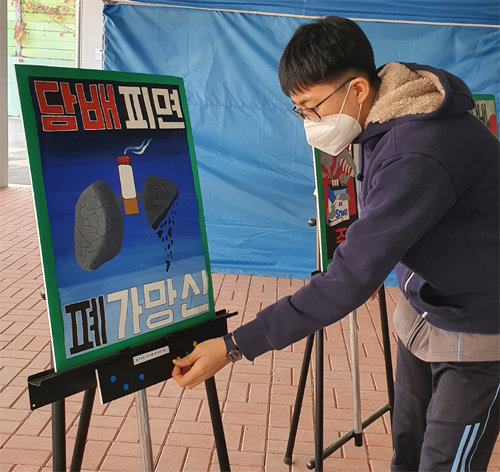 지난해 7월 서울 동대문구 전동중에서 열린 흡연예방 포스터 전시회에서 한 학생이 ‘담배 피면 폐가망신’이라고 적힌 포스터에 투표하고 있다. 서울 전동중 제공
