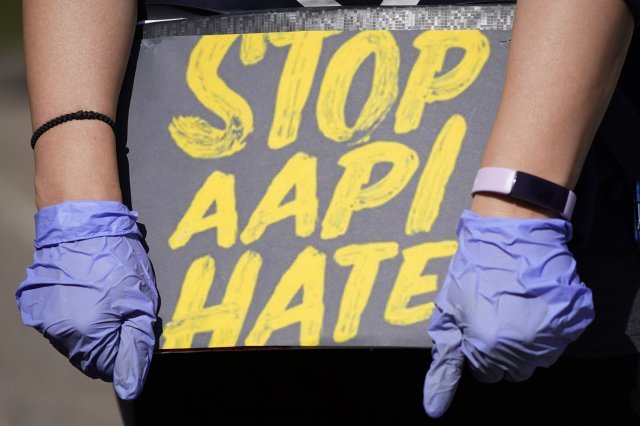 20일 시카고의 로건 스퀘어 기념비 앞에서 한 여성 시위자가 AAPI (아시아계 미국인 및 태평양 섬 주민) 증오를 막기 위한 손팻말을 들고 있다.  AP=뉴시스