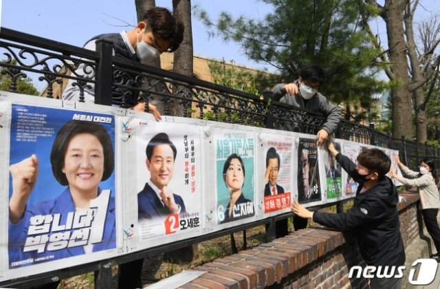 서울시선거관리위원회 직원들이 25일 서울 종로구 이화동 예술가의집 울타리에 ‘4·7 서울시장 보궐선거’에 출마하는 후보들의 선거벽보를 붙이고 있다. 뉴스1(해당 사진은 기사 내용 무관)