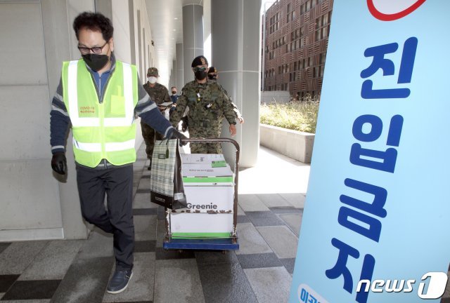 지난 30일 서울 동작구 사당동 사당종합체육관에 마련된 동작구 신종 코로나바이러스 감염증(코로나19) 백신접종센터에서 안전 수송 관계자들이 화이자 백신을 옮기고 있다. 이날 도착한 백신은 다음달 1일 75세 이상 관내 어르신들을 대상으로 접종할 계획이다. (동작구 제공) 2021.3.30