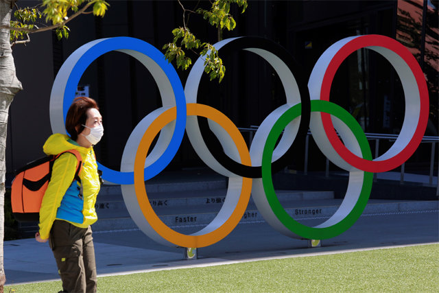일본 도쿄에서 한 시민이 마스크를 쓴 채 도쿄 올림픽 상징물 앞을 지나고 있다. 신종 코로나바이러스 감염증(코로나19)의 기세가 꺾이지 않으면 일본 국내 관중들의 올림픽 입장도 상당히 제한될 것으로 보인다. 도쿄=AP 뉴시스