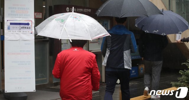 4·7 재·보궐선거 사전투표 둘째날인 3일 오전 서울 강동구 암사2동 주민센터에 마련된 사전투표소에서 우산을 쓴 시민들이 투표를 하기 위해 들어서고 있다. 2021.4.3/뉴스1 © News1
