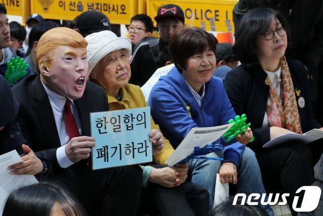 18일 오후 서울 종로구 옛 일본대사관 앞에서 열린 일본군 위안부 문제 해결을 위한 제1331차 정기 수요시위에서 한 참석자가 트럼프 가면을 쓰고 한일합의 폐기를 촉구하는 피켓을 들고 있다. 2018.4.18/뉴스1 © News1