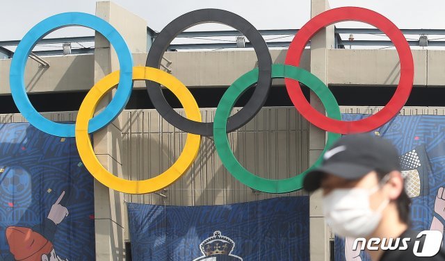 도쿄올림픽 개최를 100여일 앞두고 있는 13일 서울 송파구 잠실주경기장 오륜마크 앞으로 시민들이 지나고 있다. 교도통신에 따르면 지난달 10~12일 실시된 여론조사에서 일본 국민의 70% 이상이 올림픽 취소나 연기를 바란다는 조사 결과 나왔다. 응답자의 39.2%가 올림픽 취소를, 32.8%는 연기를 지지했다. 올림픽을 예정대로 진행해야 한다는 응답자는 24.5%에 불과했다. 이 같은 조사 결과는 최근 들어 일본 국민들 사이에서 코로나19 바이러스 확산 우려가 점점 더 높아지고 있음을 나타낸다. 2021.4.13/뉴스1 © News1