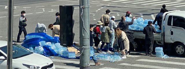 9일 오전 서울 강서구 지하철5호선 화곡역사거리에서 시민들이 도로에 쏟아진 생수 박스를 트럭에 싣고 있다. 시민 20여 명이 자발적으로 도와준 덕분에 엉망이 됐던 도로는 약 15분 만에 말끔히 정리됐다. 독자 제공
