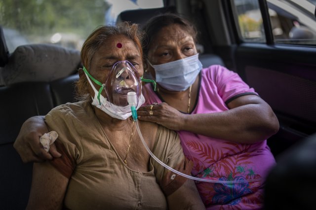 인도의 한 코로나 환자가 24일 뉴델리에 위치한 시크 교 사원으로부터 제공받은 산소통을 이용해 차 안에서 치료를 받고 있습니다. AP 뉴시스
