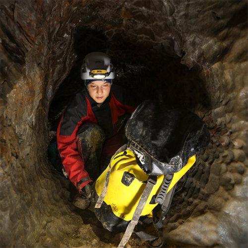 딥 타임 프로젝트에 참가한 한 여성이 좁고 축축한 지하 동굴에서 가방을 들고 이동하고 있다. HAI 제공