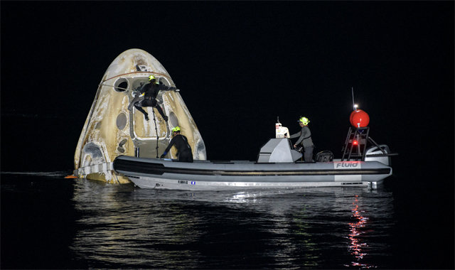 2일 오전(현지 시간) 미국 우주개발기업 스페이스X의 유인 우주선 ‘크루드래건’ 캡슐이 플로리다주 멕시코만 바다에 성공적으로 내려앉아 떠 있다. 사진 속 캡슐 안에 우주인 4명이 타고 있는 상태다. 미리 보트에서 귀환을 기다리던 지원팀이 캡슐의 상태를 살펴보고 있다. AP 뉴시스