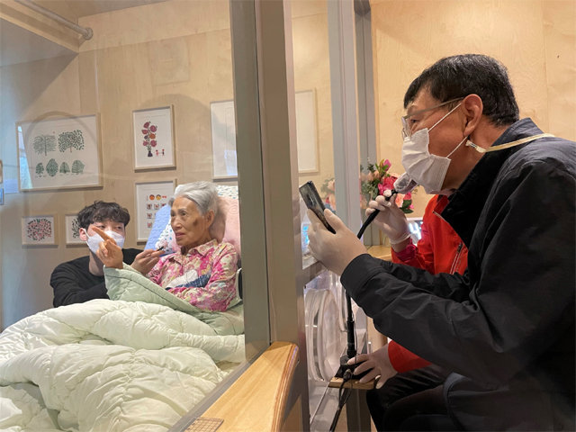 지난달 20일 서울 시립동부노인요양센터 비대면 면회실에서 이외분 할머니(86)가 화면에 뜬 손녀의 결혼식 영상을 보면서 아들과 마이크로 대화를 나누고 있다. 서울시 제공