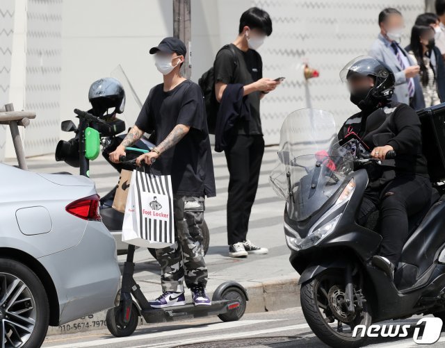 전동킥보드 등 개인형 이동장치(PM)의 이용 규제를 강화하는 개정 도로교통법 시행이 시작된 13일 오후 서울 마포구 홍익대 정문 앞에서 한 시민이 헬멧 없이 전동킥보드를 이용하고 있다. © News1