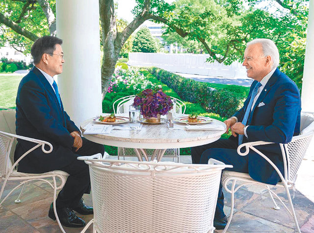 원형 테이블 사이에 두고 오찬 문재인 대통령(왼쪽)과 조 바이든 미국 대통령이 21일(현지 시간) 백악관 오벌 오피스 야외 테라스에서 메릴랜드 크랩 케이크가 메뉴로 오른 오찬을 겸한 단독 회담을 갖고 있다. 조 바이든 대통령 트위터