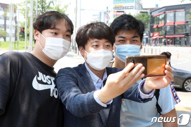 국민의힘 당 대표 출마를 선언한 이준석 전 최고위원이 24일 오후 대구 북구 경북대학교 북문 앞에서 대학생들과 인사 나누며 기념사진을 찍고 있다. 2021.5.24/뉴스1 © News1