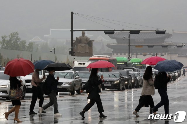 전국 대부분 지역에 ‘황사비’가 내린 25일 오전 서울 종로구 광화문 네거리에서 우산을 쓴 시민들이 출근길 발걸음을 재촉하고 있다. 2021.5.25/뉴스1 © News1