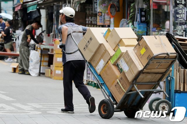 서울 남대문시장에서 택배기사가 짐을 싣은 손수레를 끌고 가고 있다./뉴스1 © News1