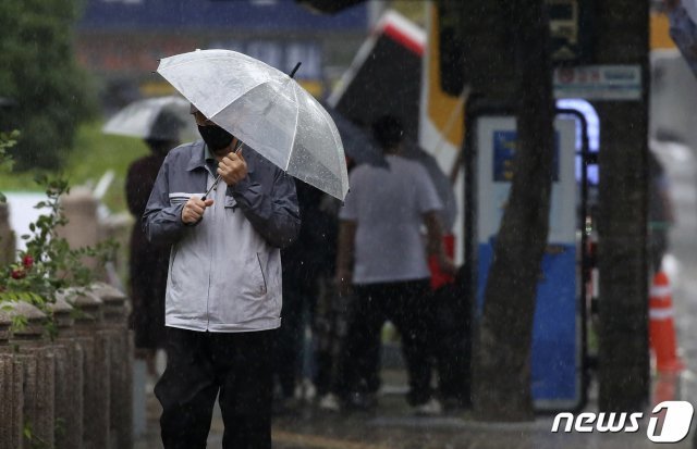 울산지역에 비가 내리는 28일 오후 울산 남구 한 거리에서 시민이 우산을 부여잡고 걷고 있다. 기상청은 이날 오후 2시를 기해 울산에 강풍주의보를 발효했다. 2021.5.28/뉴스1 © News1