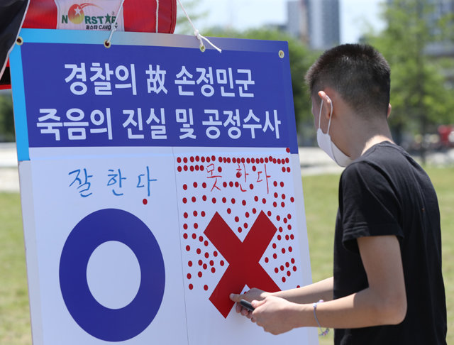 30일 서울 서초구 반포한강공원에 마련된 고 손정민 씨 추모 공간에서 한 시민이 한 설문조사에 스티커를 붙이고 있다. 경찰은 손 씨와 함께 있던 A 씨에 대해 범죄를 의심할 만한 근거를 찾지 못했다는 입장이지만 유족 측은 수사에 대한 의문을 거듭 제기하고 있다. 뉴스1