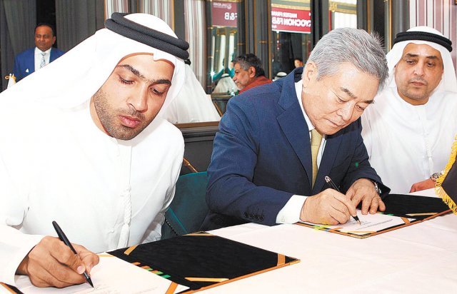 소진세 교촌에프앤비㈜ 회장(가운데)이 4월 UAE 두바이에서 열린 ‘교촌에프앤비-갈라다리 브러더스 그룹과의 마스터 프랜차이즈 계약 체결식’에서 서명을 하고 있다.