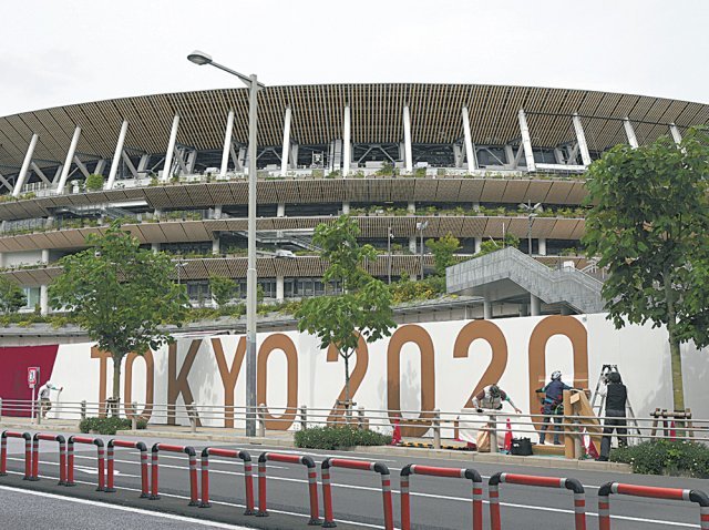 2일 도쿄 올림픽 개막식이 열리는 일본 도쿄의 국립경기장 담장을 인부들이 홍보물로 덮어씌우고 있다. 도쿄=AP 뉴시스