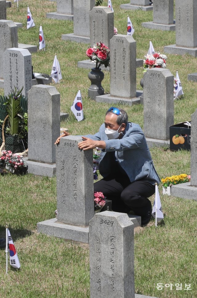 한 참배객이 먼저 세상을 떠난 공군사관학교 동기생의 묘비에 손을 올린 후 참배하고 있다.  .김동주기자 zoo@donga.com
