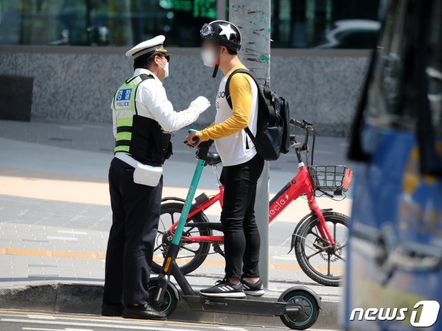 전동킥보드 등 개인형 이동장치(PM)의 이용 규제를 강화하는 개정 도로교통법 시행이 시작된 13일 오후 서울 마포구 홍대입구역 인근 인도에서 마포경찰서 경찰들이 전동킥보드를 이용하는 시민에게 재개정 관련 내용 홍보 및 계도를 하고 있다. 2021.5.13/뉴스1 © News1