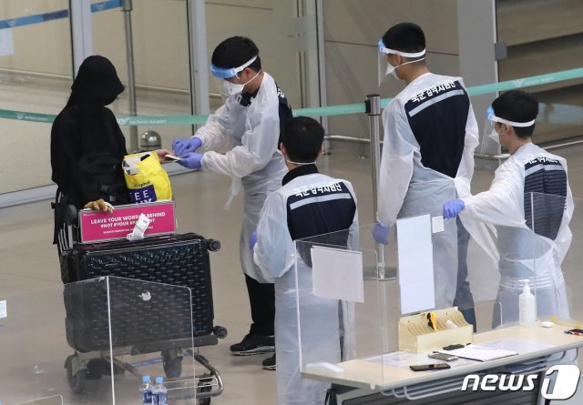 인천국제공항 제2여객터미널에서 방역 관계자들이 해외 입국자들에게 동선을 안내하고 있다./뉴스1 © News1