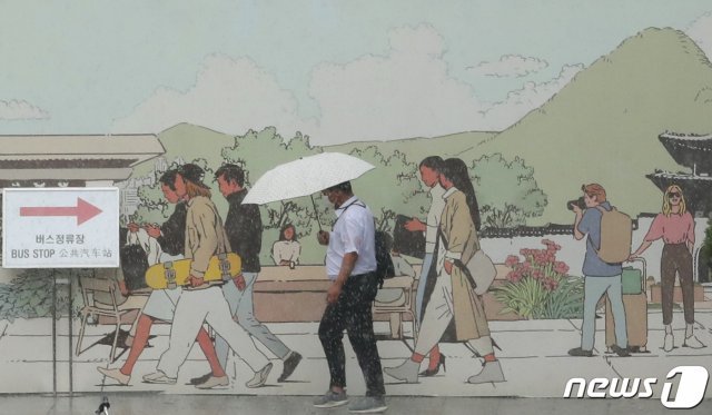 소나기가 쏟아진 23일 오후 서울 종로구 정부서울청사 인근 인도에서 우산을 쓴 시민이 걸음을 재촉하고 있다. 2021.6.23/뉴스1 © News1