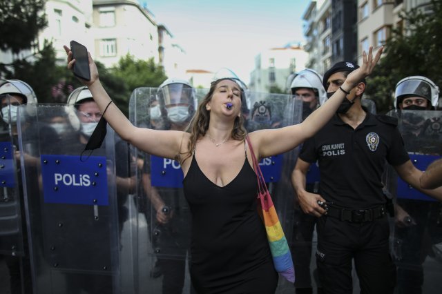 26일 터키 이스탄불에선 코로나19 감염 우려로 퀴어 행사가 금지됐다. 한 여성이 경찰을 배경으로 항의의 의미로 춤을 추고 있다. AP 뉴시스