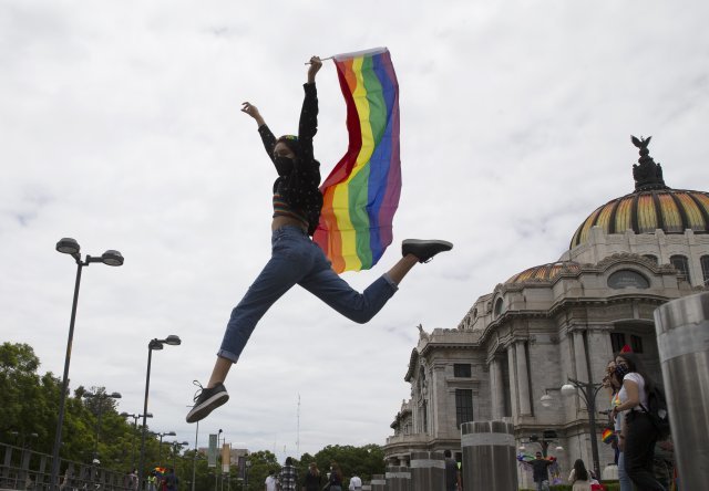 26일(현지시간) 멕시코 시티에서 한 여성이 퀴어 퍼레이드 행사를 축하하기 위해 무지개색 깃발을 들고 카메라를 향해 멋진 포즈를 취하고 있다. AP 뉴시스