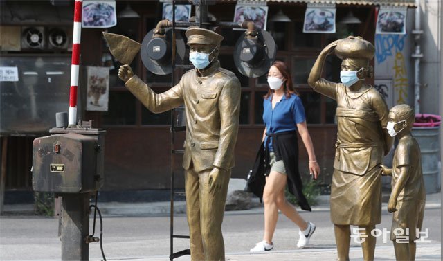 서울 마포구 동교동 경의선숲길에서 마스크를 씌운 동상들 옆을 마스크를 쓴 여성이 지나고 있다. 코로나19 팬데믹과 함께 등장한 마스크는 ‘제2의 피부’라고 불릴 만큼 일상에 큰 변화를 가져왔다. 홍진환 기자 jean@donga.com