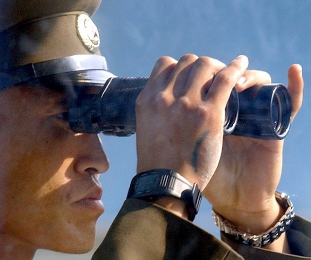 양쪽 손목에 시계를 찬 북한 병사가 망원경으로 남쪽 지역을 살펴보고 있다. 오른쪽 손엔 격파 훈련으로 생긴 것으로 보이는 멍 자국이 있다. 박영대 기자. 2004년 11월 9일 촬영.