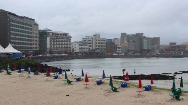 [제주=뉴시스] 장마가 시작된 3일 오전 제주시 함덕해수욕장에서 일부 관광객이 우산을 쓰고 물에 발을 담그고 있다. 이날 시작된 제주지역 장마는 1982년 7월5일 이후 가장 늦게 온 장마다. 2021.07.03.