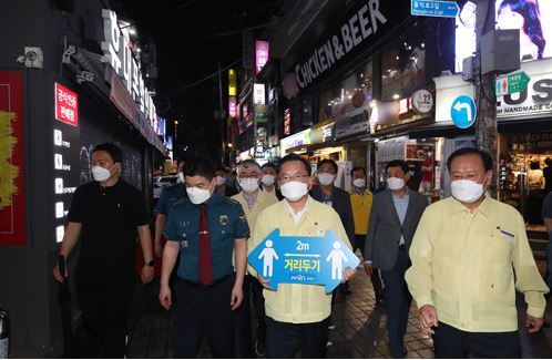 김부겸 국무총리(가운데)가 7일 서울 마포구 홍익대 인근에서 ‘2m 거리 두기’ 팻말을 들고 현장 점검에 나섰다. 최근 서울 강남과 마포 등 젊은이들이 자주 찾는 지역의 주점과 식당을 중심으로 코로나19 신규 확진자가 늘고 있다. 동아일보